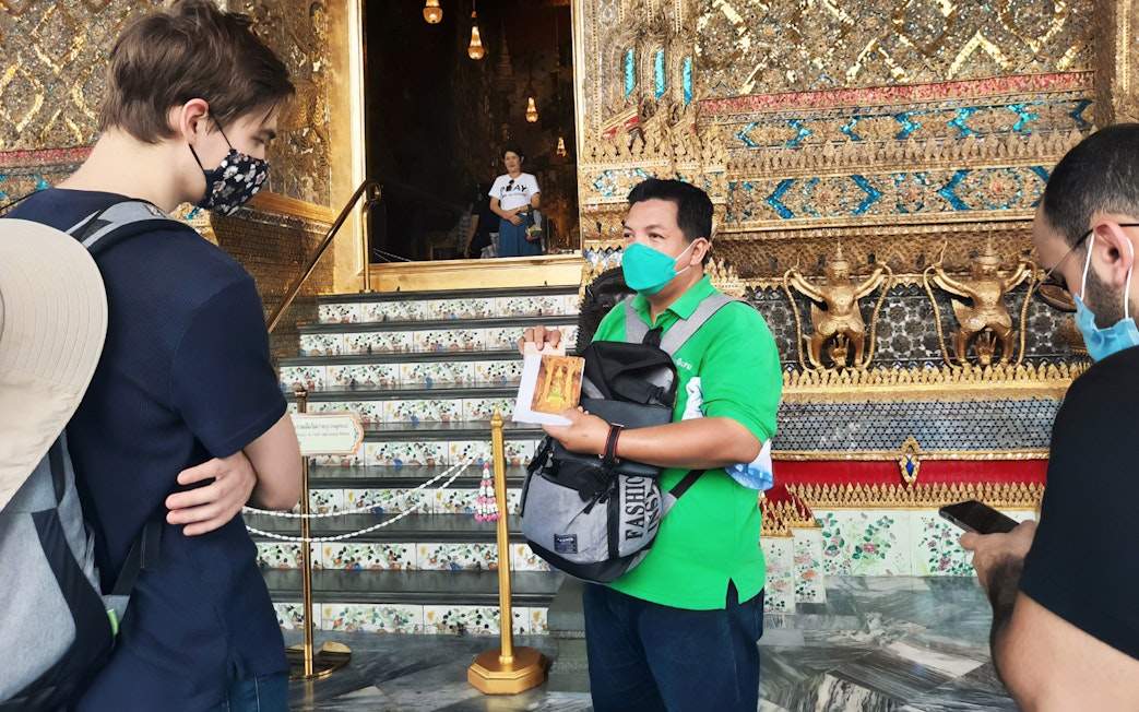 Tour guide explaining details at Grand Palace entrance, Bangkok.