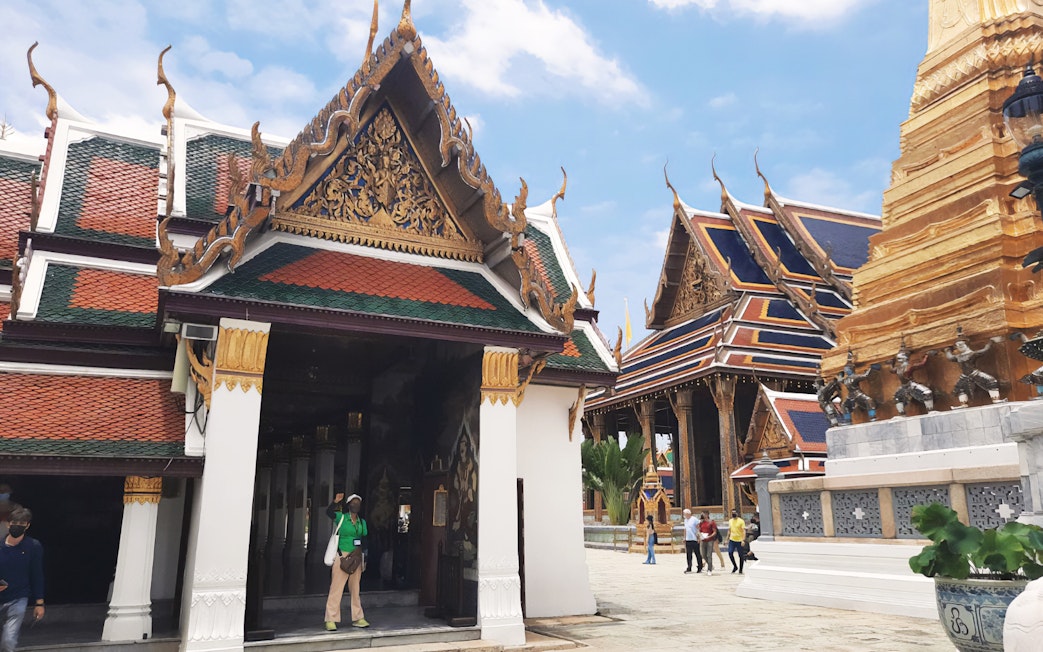 Grand Palace and Wat Phra Kaew buildings with tourists exploring the temple grounds in Bangkok.