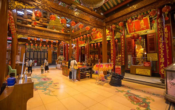 Chinatown temple interior with red lanterns and visitors, Bangkok walking tour.