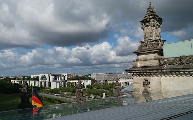 Reichstag building view with German flag and Berlin cityscape during guided tour.