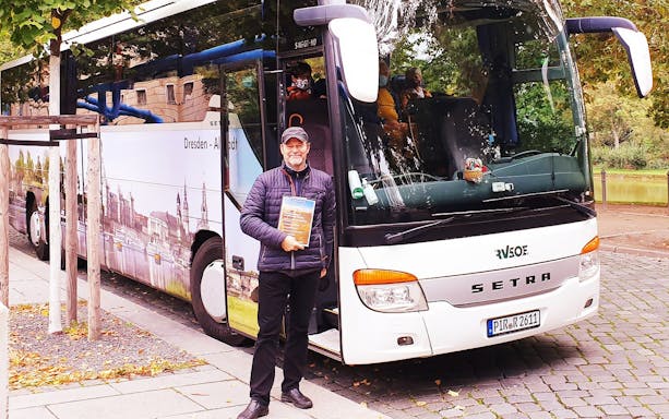 Tour guide standing beside a tour bus for the Half-Day Tour to Meissen and Moritzburg Castle from Dresden.