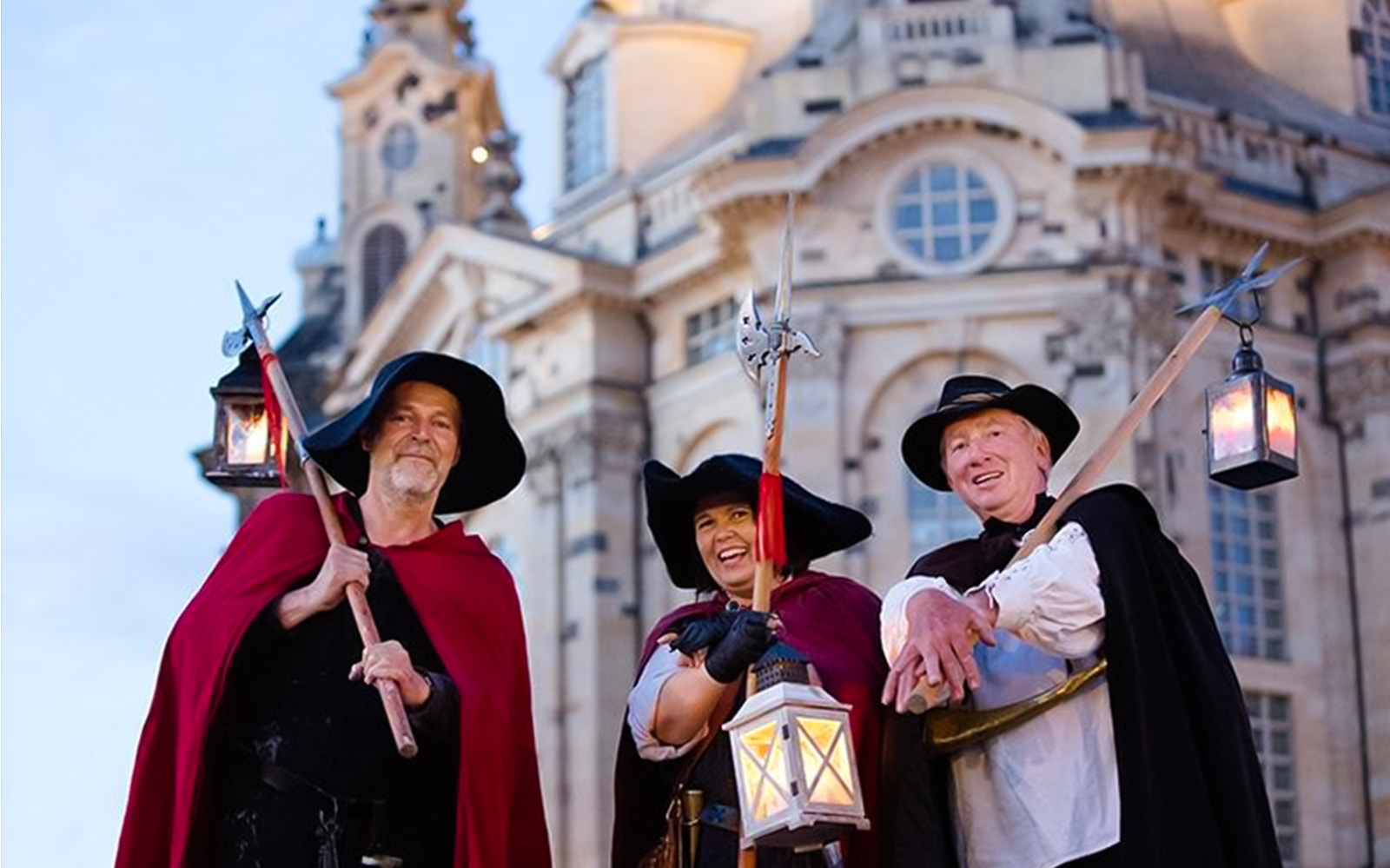Night watchmen in traditional attire with lanterns in front of Dresden's Frauenkirche.