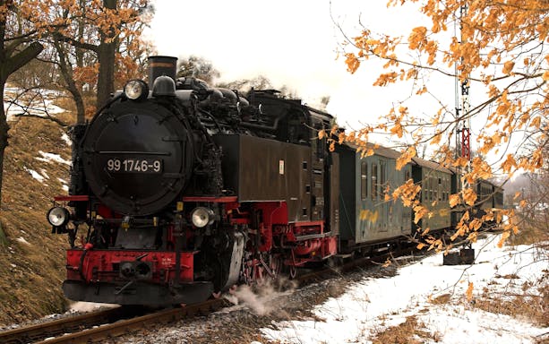 Steam train traveling through snowy landscape in Dresden, Germany.