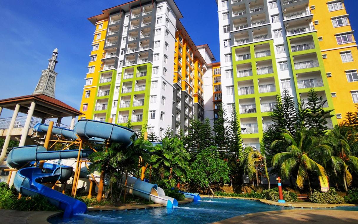 Water slide and pool at Bayou Lagoon Water Park with colorful buildings in the background.