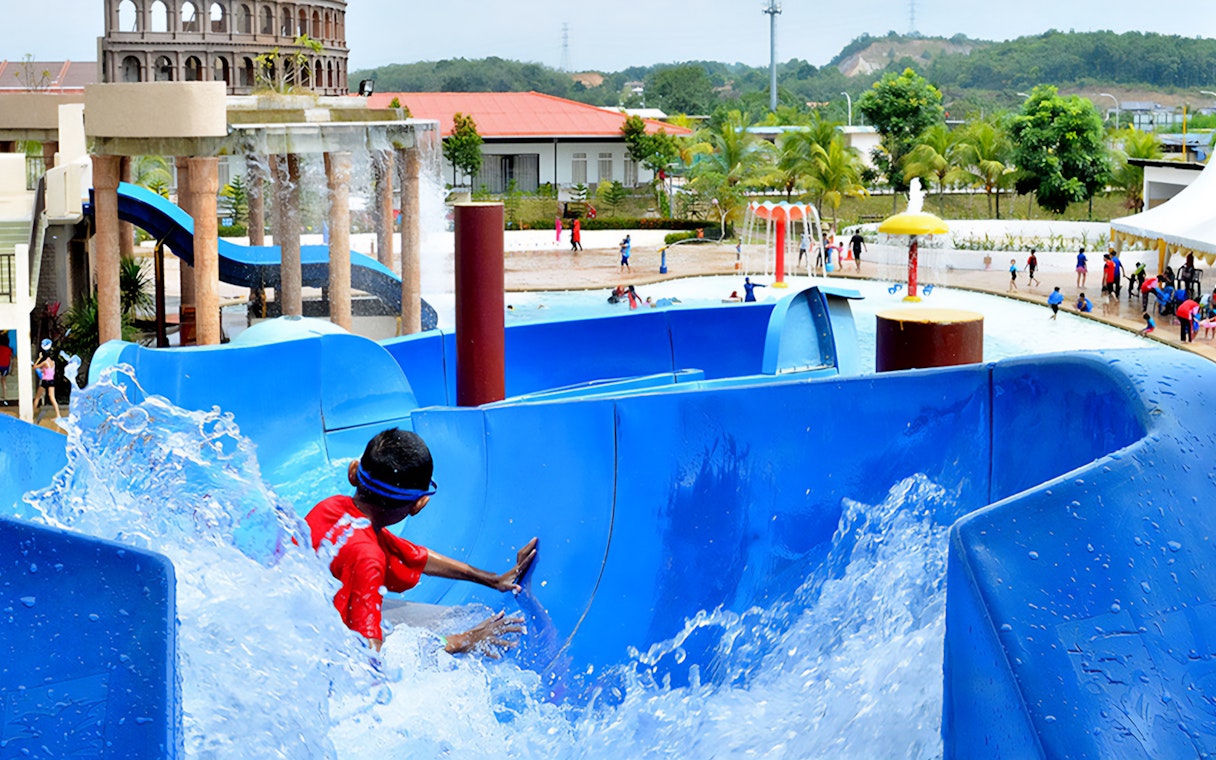 Child sliding down a blue water slide at Bayou Lagoon Water Park.
