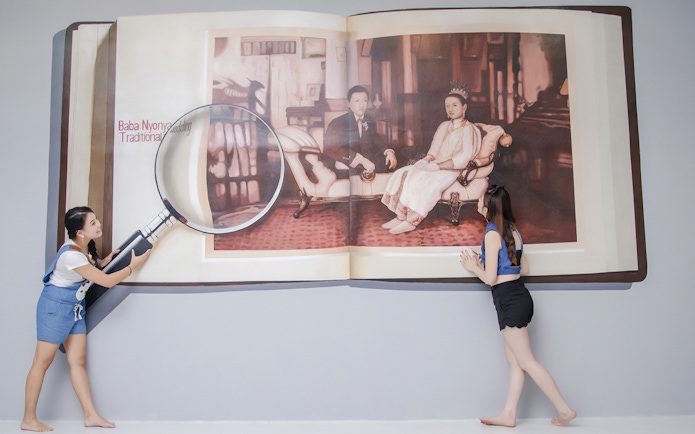 Visitors interact with a 3D art installation of a magnified book at Magic Art 3D Museum.