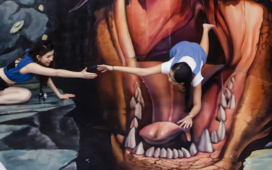 Visitors interacting with 3D art at Magic Art 3D Museum, creating an illusion of being inside a creature's mouth.