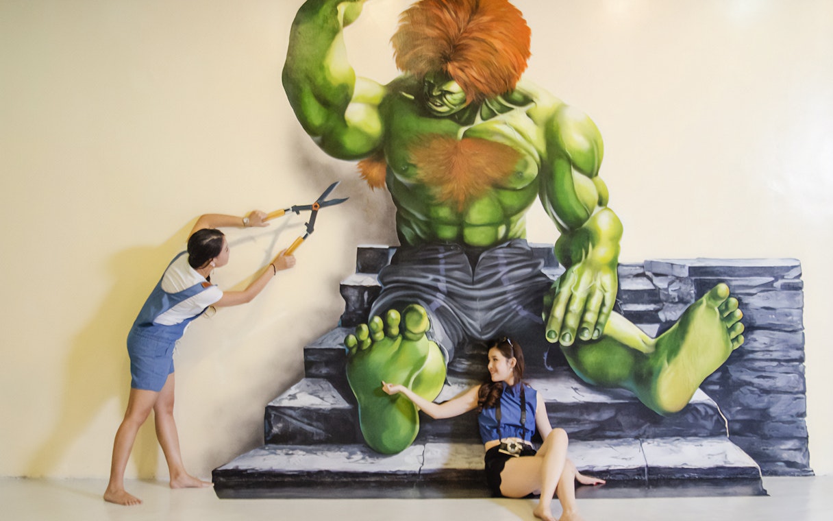 Visitors interacting with a 3D mural of a green giant at Magic Art 3D Museum.
