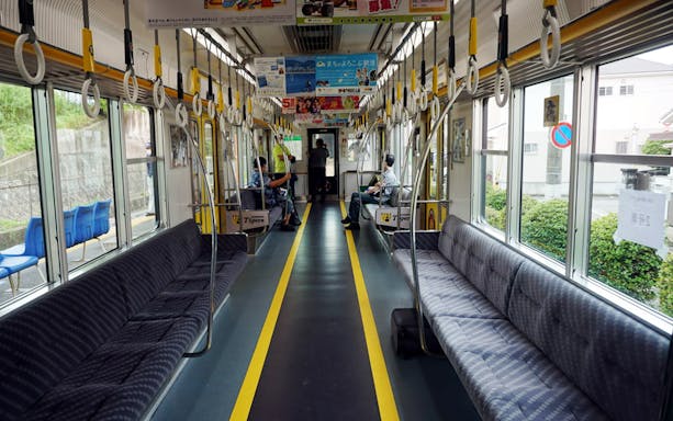 Interior of a Hanshin train in Japan, showcasing seating and handrails.