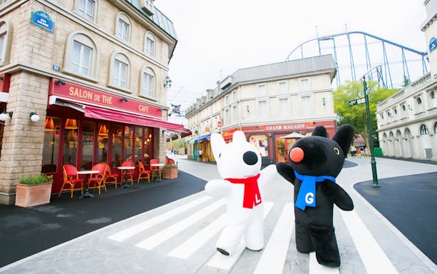 Mascots at Fuji Q Highland amusement park, Japan, near a themed café and shops.