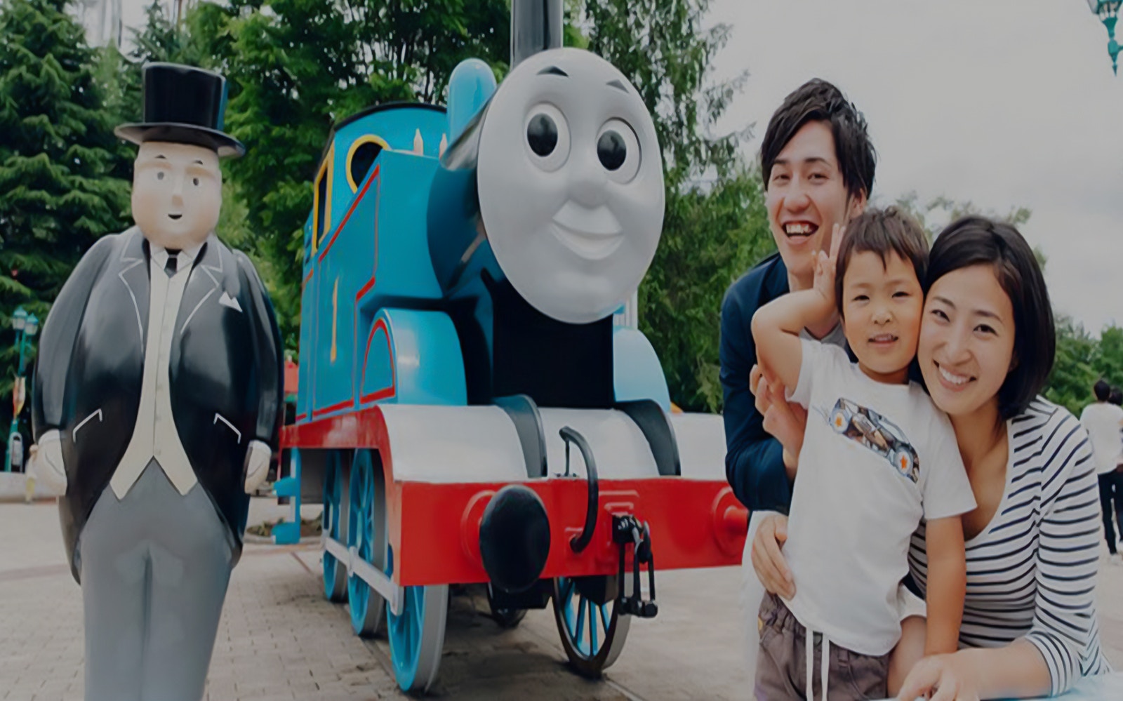 Family posing with Thomas the Tank Engine and character statue at FujiQ Highland.