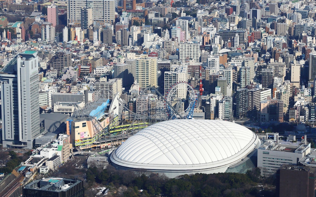 Tokyo Dome City with amusement park rides and surrounding cityscape.