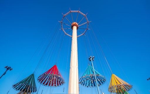 Colorful swing ride at Tokyo Dome City Attractions against a clear blue sky.