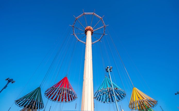 Colorful swing ride at Tokyo Dome City Attractions against a clear blue sky.