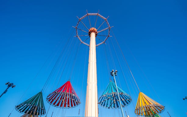 Colorful swing ride at Tokyo Dome City Attractions against a clear blue sky.