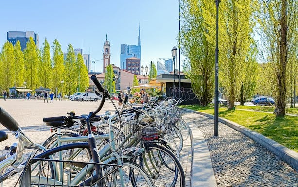 Bicycles lined up in a Milan square with modern and historic buildings in the background.