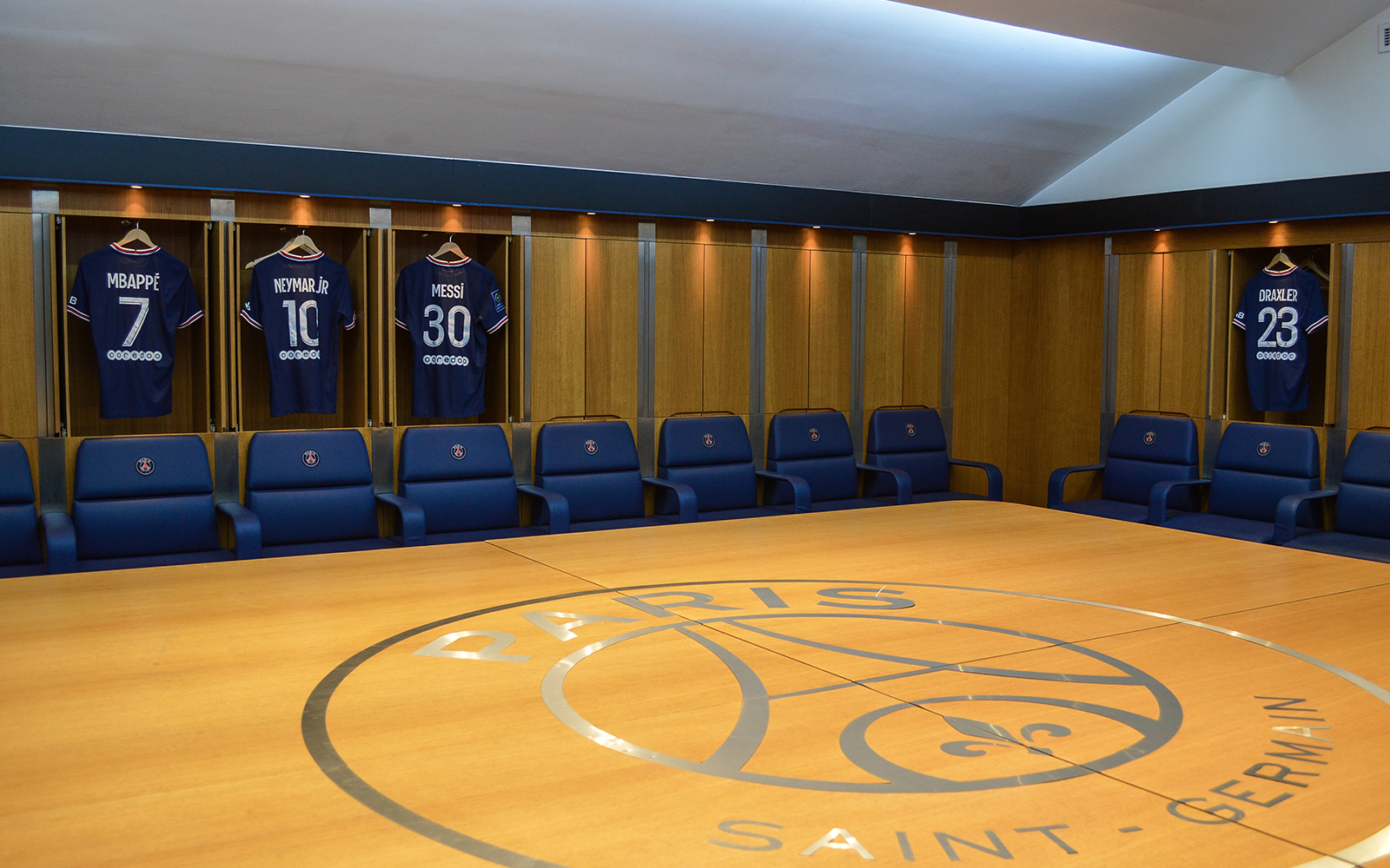 Paris Saint-Germain locker room with player jerseys at Parc des Princes Stadium.