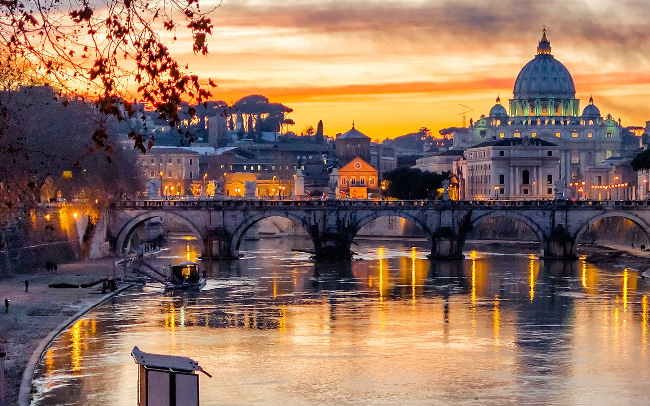 Sunset view of St. Peter's Basilica and Sant'Angelo Bridge in Rome, Italy.