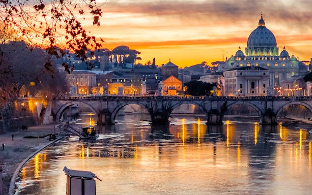 Sunset view of St. Peter's Basilica and Sant'Angelo Bridge in Rome, Italy.