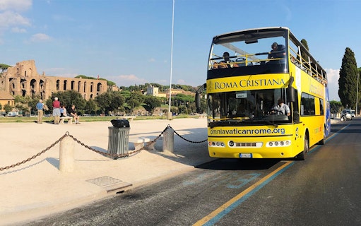Yellow open-top bus near Roman ruins, Vatican&Rome Open Bus Service.