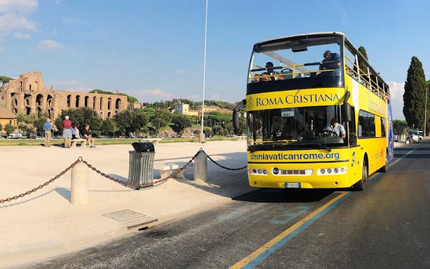 Yellow open-top bus near Roman ruins, Vatican&Rome Open Bus Service.