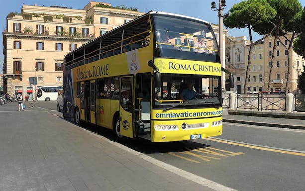 Vatican&Rome open-top tour bus on city street near historic buildings.