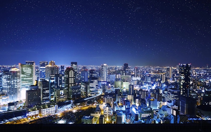 Night view of Osaka cityscape from Umeda Sky Building, illuminated buildings and starry sky.