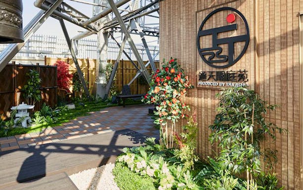 Tsutenkaku Tower garden area with plants and signage in Osaka, Japan.