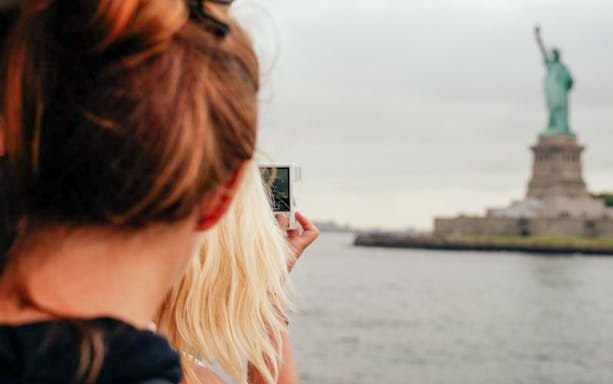 Tourists photographing the Statue of Liberty from a ferry in New York City.