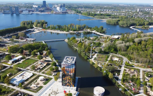 Aerial view of Floriade Expo 2022 site with waterways and Almere cityscape in the background.