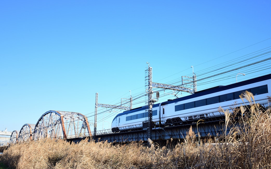 Tokyo Skyliner train crossing a bridge under a clear blue sky.