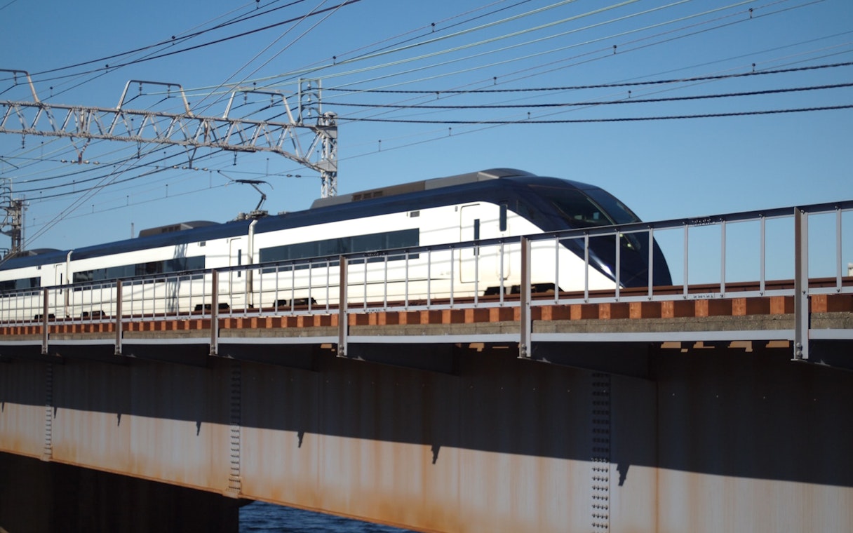 Tokyo Skyliner Express train crossing a bridge under clear blue sky.