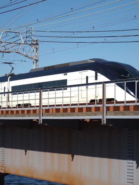 Tokyo Skyliner Express train crossing a bridge under clear blue sky.