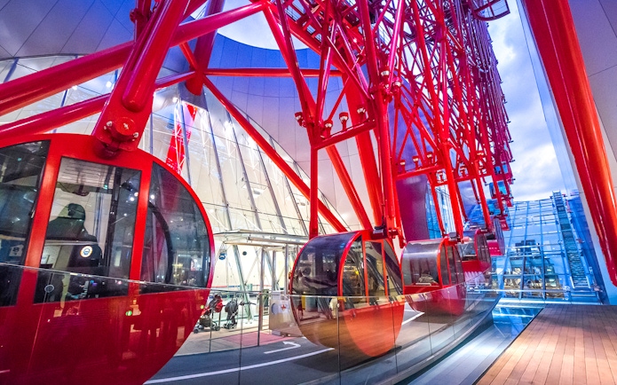 Red gondolas of the HEP Ferris Wheel in a modern glass building.