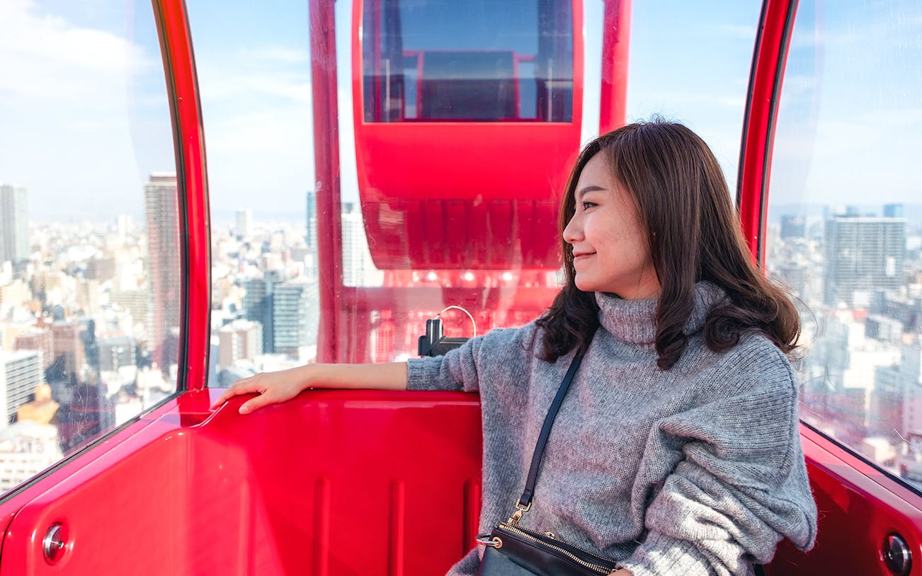 Person enjoying city view from HEP Ferris Wheel cabin in Osaka.