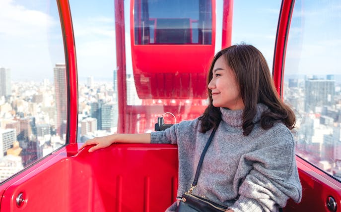Person enjoying city view from HEP Ferris Wheel cabin in Osaka.