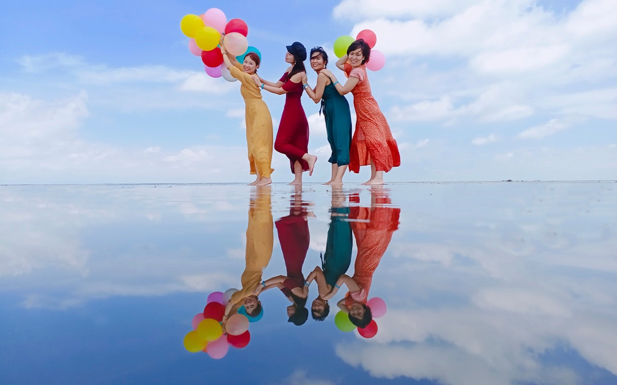 Group enjoying Sky Mirror Experience in Kuala Selangor with colorful balloons reflected on water.