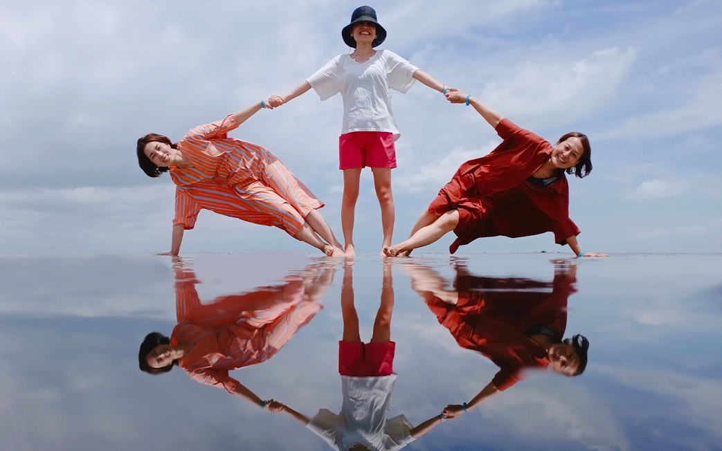 Three people posing on reflective water at Sky Mirror, Kuala Selangor.