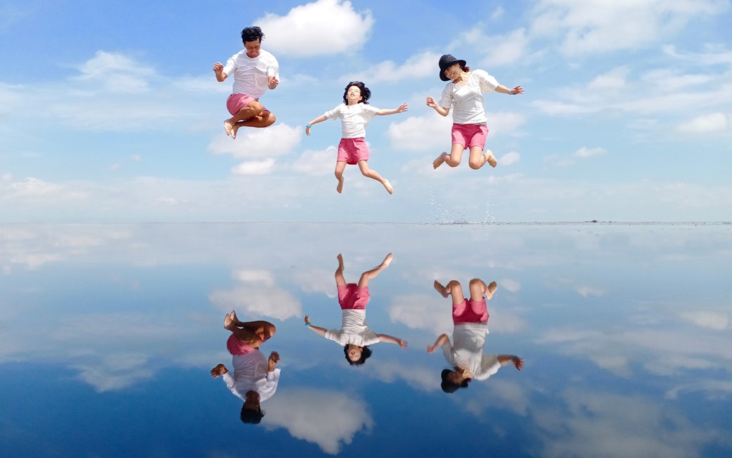 People jumping with reflections on water at Sky Mirror, Kuala Selangor.