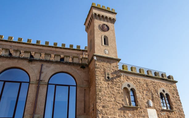 Stone tower and arched windows of a historic building in Sutri Pass, Italy.