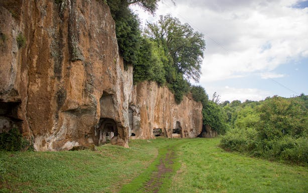 Ancient rock formations along Sutri Pass with greenery and a dirt path.