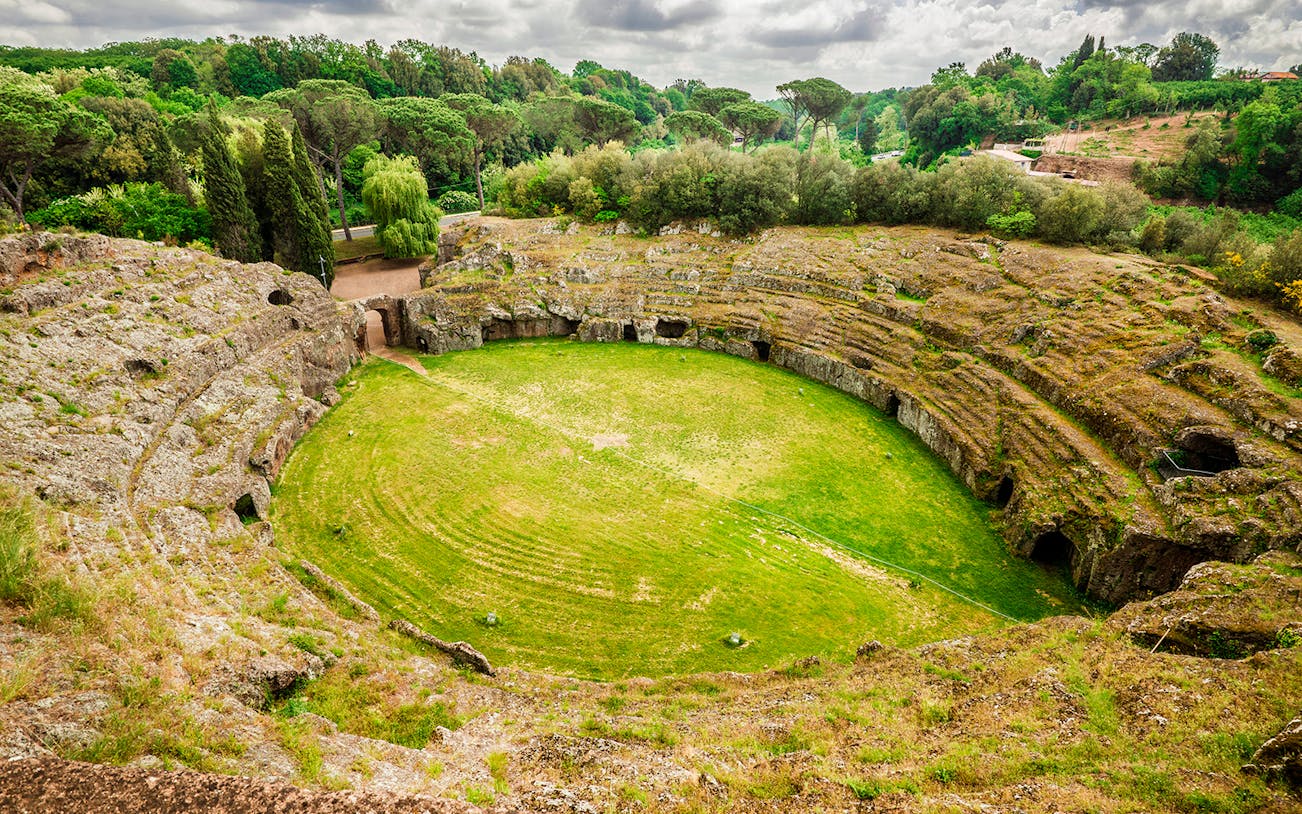Ancient amphitheater in Sutri, Italy, surrounded by lush greenery.