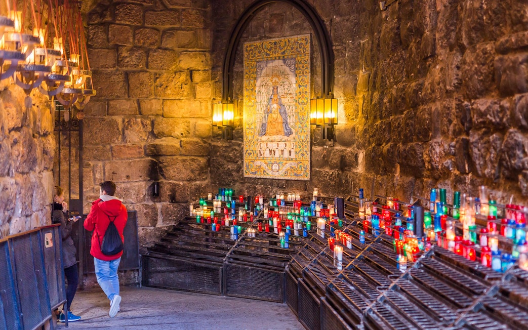 Visitors exploring Montserrat Monastery with colorful candles and religious artwork.
