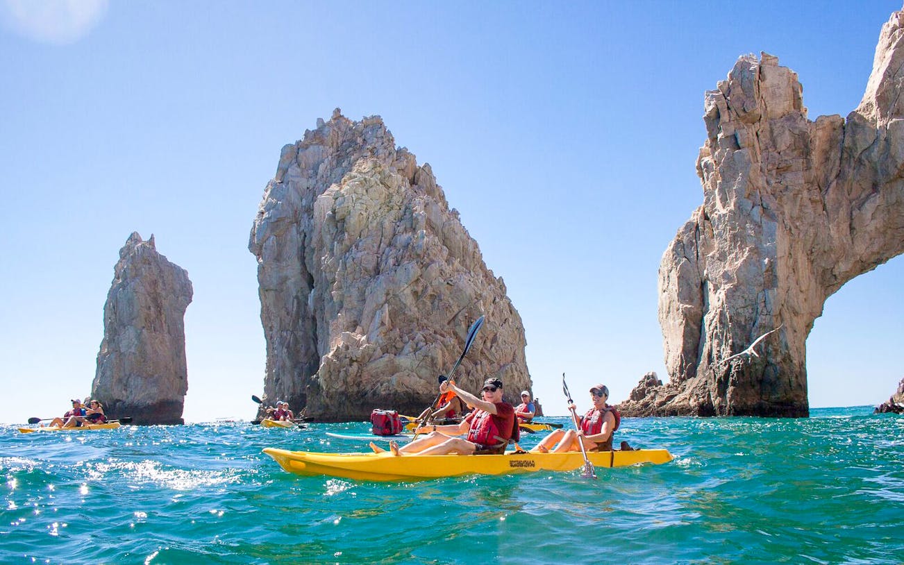 Kayakers near rock formations in Cabo San Lucas during a guided tour.