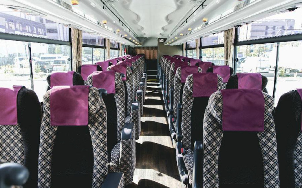 Interior of Kansai Airport bus with rows of patterned seats and purple headrests.