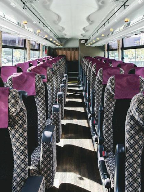 Interior of Kansai Airport bus with rows of patterned seats and purple headrests.
