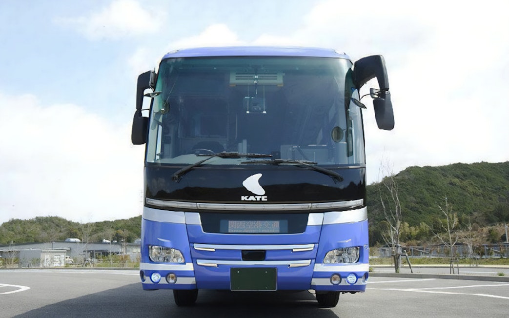 Kansai Airport bus parked in a lot with a scenic background.