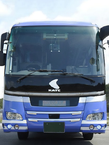 Kansai Airport bus parked in a lot with a scenic background.
