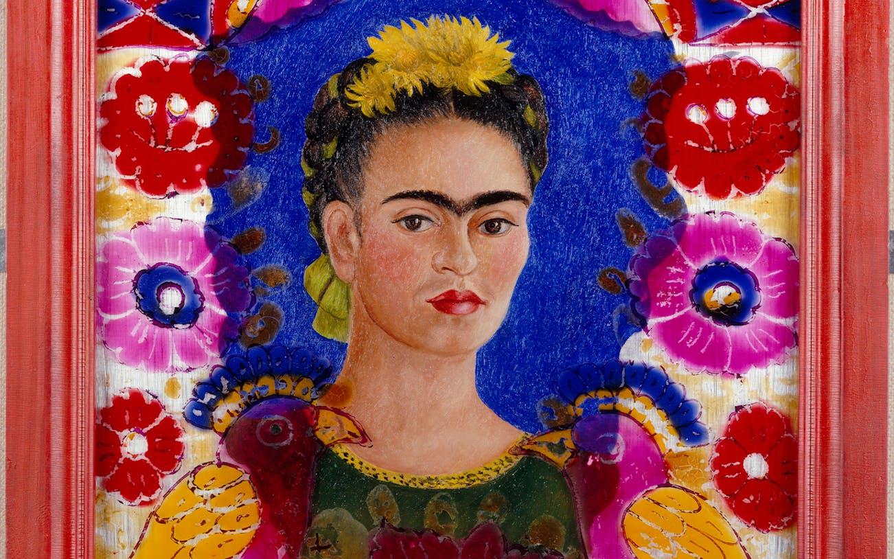 Frida Kahlo portrait with colorful floral background at Palais Galliera exhibition.