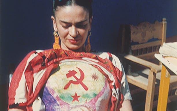 Frida Kahlo wearing a colorful blouse with a hammer and sickle design at Palais Galliera exhibition.